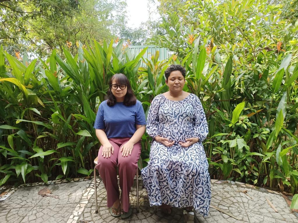 Priyanka on the left sitting with her beneficiary migrant on the right .