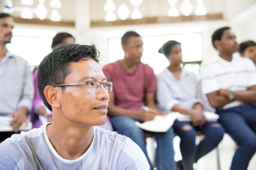 A group of participants looking at something where one participant is sitting in front